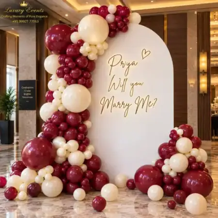 Marry Me setup in DLF Phase 3 Gurugram with white arch backdrop, personalized neon script and burgundy balloons